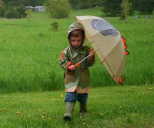 Rompicapo di Bambino con il suo ombrello e giacca pioggia in pioggia di primavera