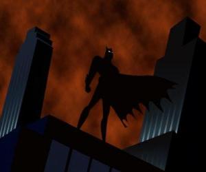 Rompicapo di Batman, il uomo pipistrello, guardando la città dal tetto di un edificio a Gotham City