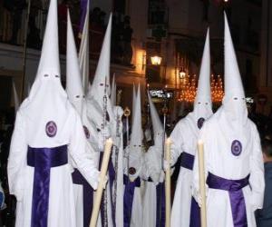 Rompicapo di Nazareni o  penitenti in una processione durante la Settimana Santa con il cappuccio o un cono, tunica e mantello