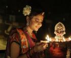 Donna in ginocchio con un olio della lampada in mano nella celebrazione del Diwali