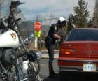 Funzionario di polizia motorizzata con la sua moto e mettere una multa ad un conducente