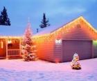 Casa decorata con decorazioni natalizie e di due alberi di Natale nel giardino