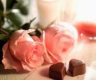 Due rose rosa con due a forma di cuore cioccolatini