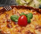 Una squisita lasagne al forno decorate con una ciliegina di pomodoro e qualche foglia