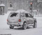 Un'auto passando per una città completamente nevada in inverno